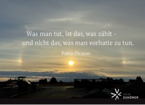 Sonnenaufgang mit Halo über einer Landschaft – Symbol für Bewusstsein, Neubeginn und aus dem Funktioniermodus aussteigen. Zitat von Pablo Picasso: „Was man tut, ist das, was zählt – und nicht das, was man vorhatte zu tun.“