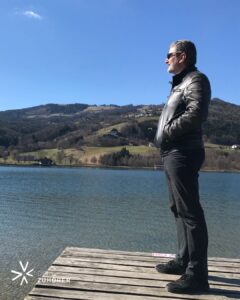 Mann steht ruhig auf einem Steg am See und blickt in die Weite – Symbol für Gelassenheit und innere Ruhe