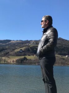 Mann steht ruhig auf einem Steg am See und blickt in die Weite – Symbol für Gelassenheit und innere Ruhe